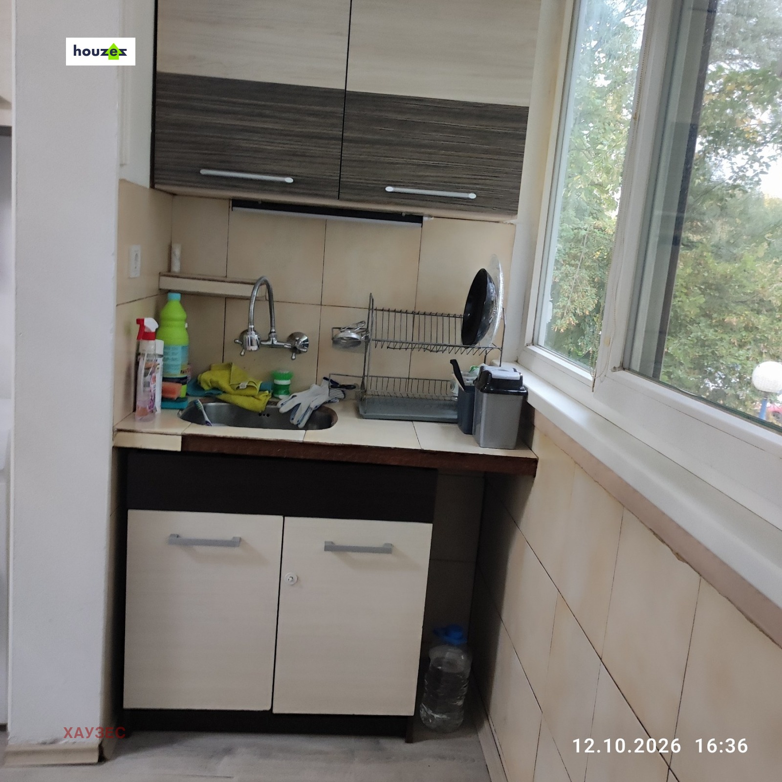 Kitchen sink corner with upper cabinets, tile backsplash, and garden window