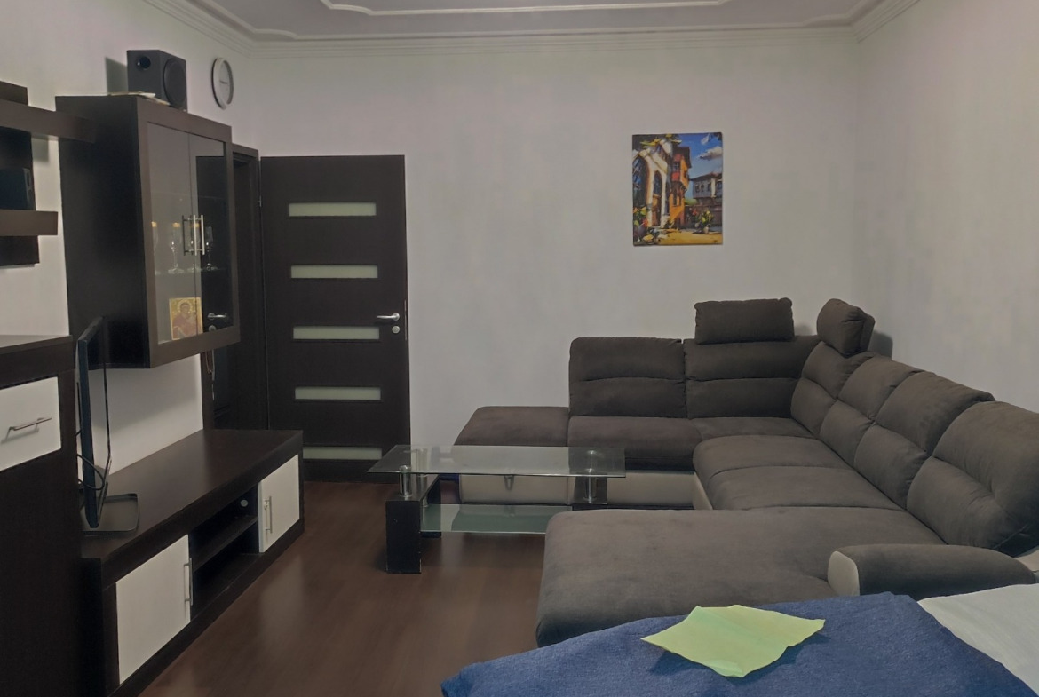 Living room with large corner sofa, glass coffee table, and TV unit