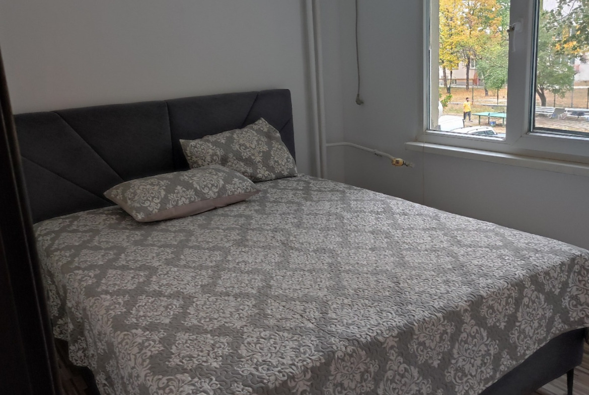Bedroom with dark upholstered double bed and window overlooking courtyard