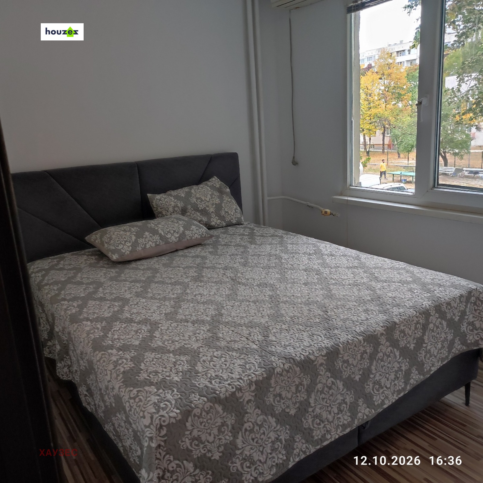 Bedroom with dark upholstered double bed and window overlooking courtyard