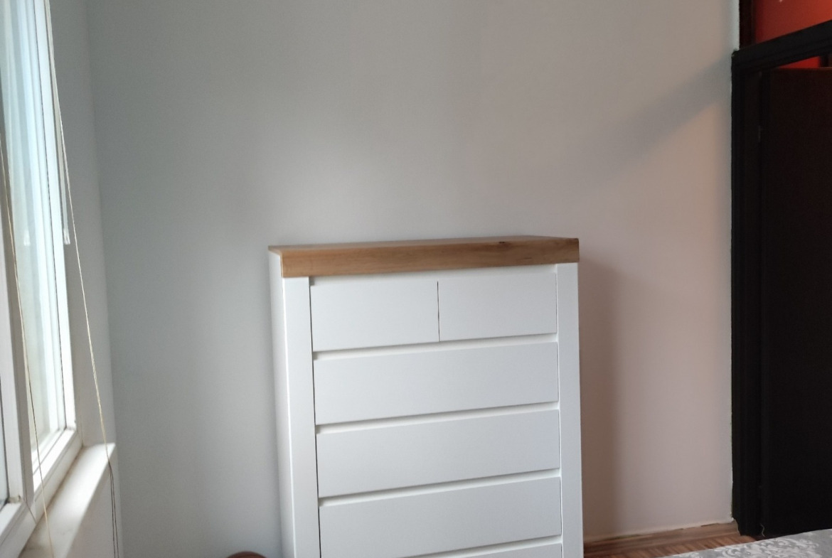 Bedroom corner with white chest of drawers and wooden top surface