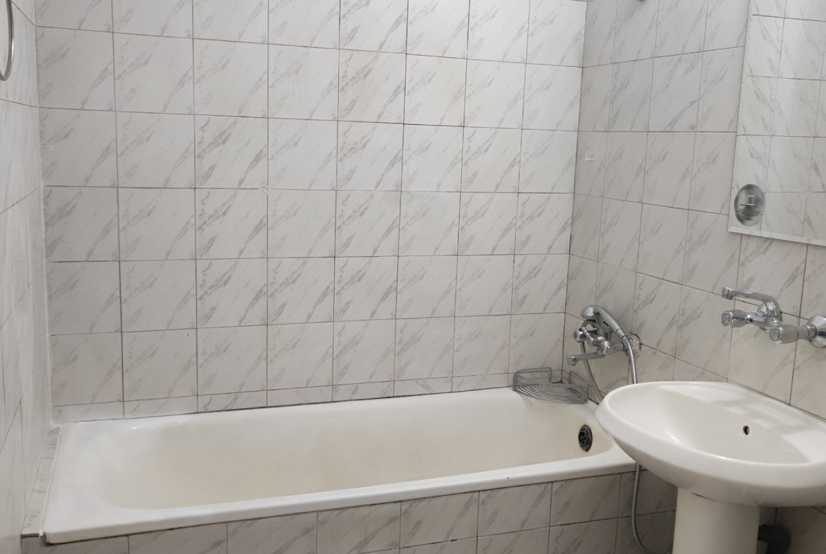 Bathroom with white marble-effect wall tiles, bathtub, and pedestal sink