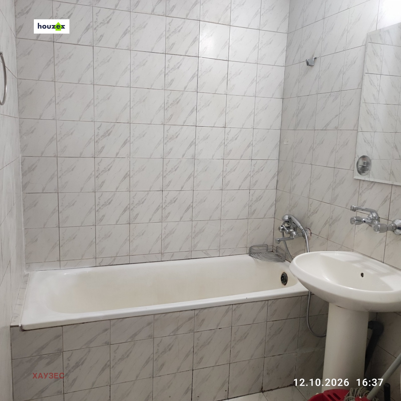 Bathroom with white marble-effect wall tiles, bathtub, and pedestal sink
