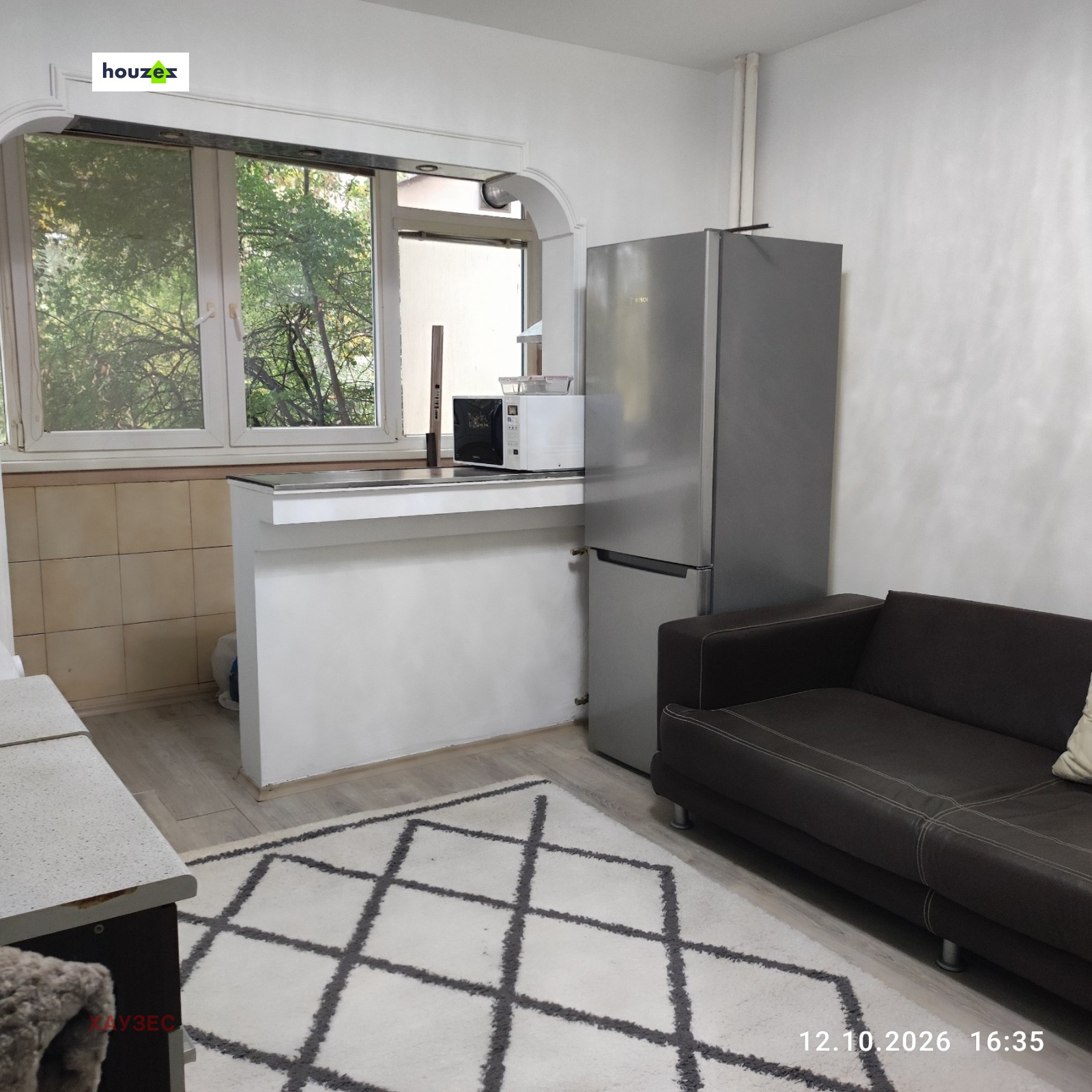 Kitchen area with stainless steel fridge, small sofa, and garden view