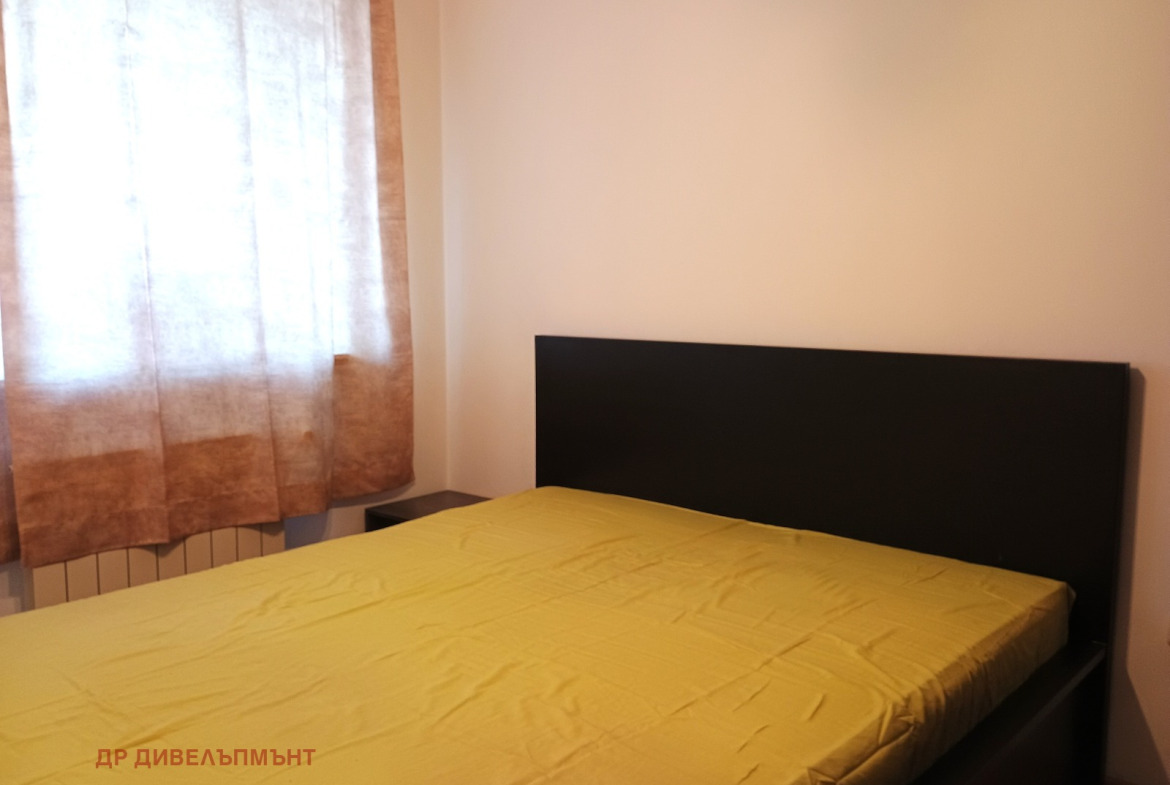 dvustaen-apartament-68-sqm-pod-naem-darvenitsa-sofiya-blizo-do-metro-12 Спалня с двойно легло, тъмно табло, жълта покривка и прозорец със завеси