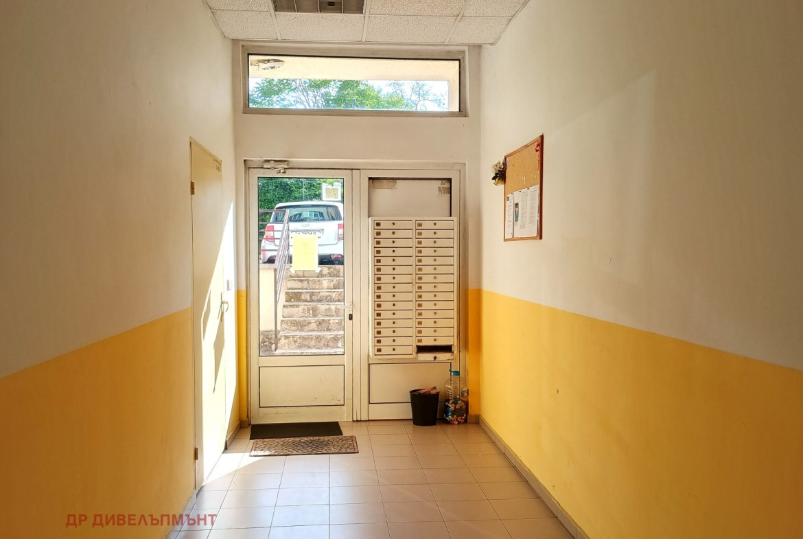 dvustaen-apartament-68-sqm-pod-naem-darvenitsa-sofiya-blizo-do-metro-17 Входно фоайе на сградата с пощенски кутии, стъклена входна врата и жълто боядисани долни стени