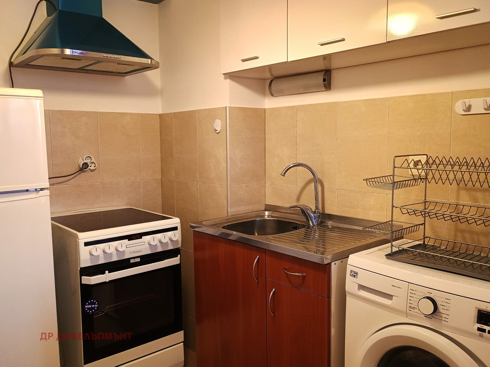 dvustaen-apartament-68-sqm-pod-naem-darvenitsa-sofiya-blizo-do-metro-8 Кухня с мивка от неръждаема стомана, електрическа печка, перална машина и стенни шкафове