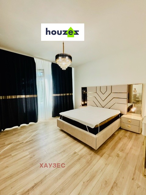 One-Bedroom Apartment bedroom with upholstered bed, chandelier, dark curtains, light wood floor, Sofia