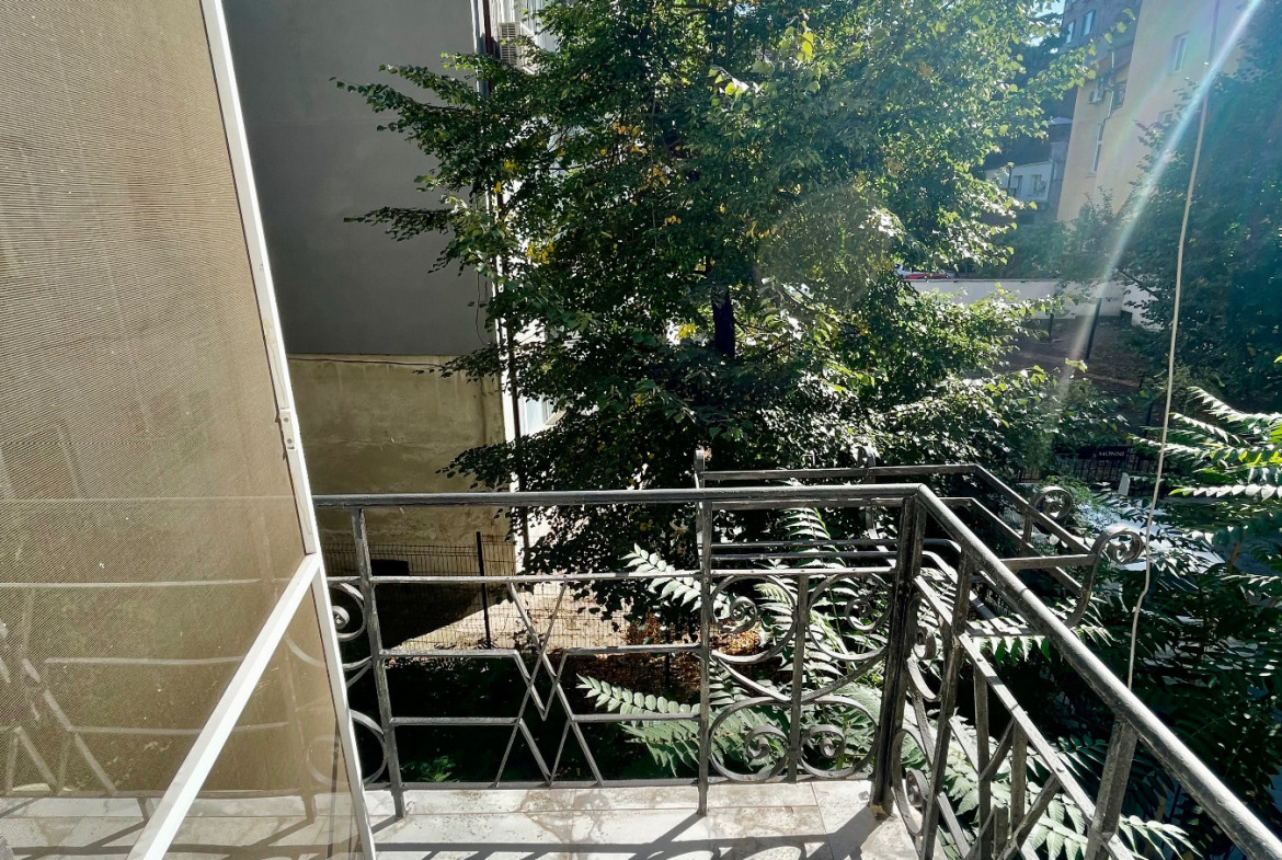Balcony with wrought iron railing overlooking trees and neighbouring buildings