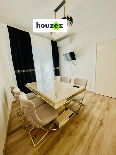 Dining room with mirrored gold table, beige chairs, wall-mounted TV, air conditioner
