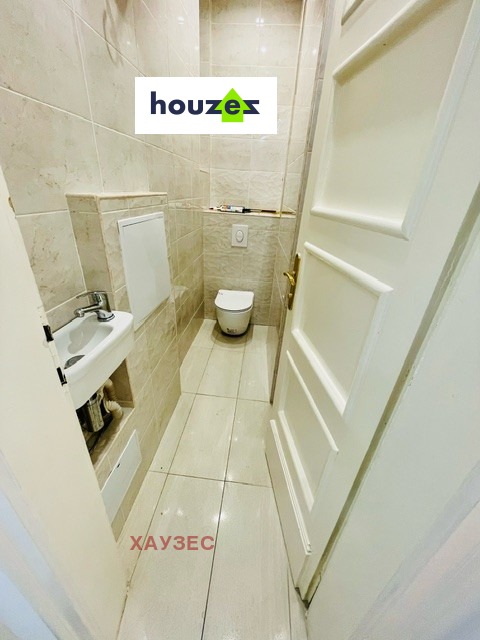 Narrow separate toilet room with wall-mounted toilet and small basin
