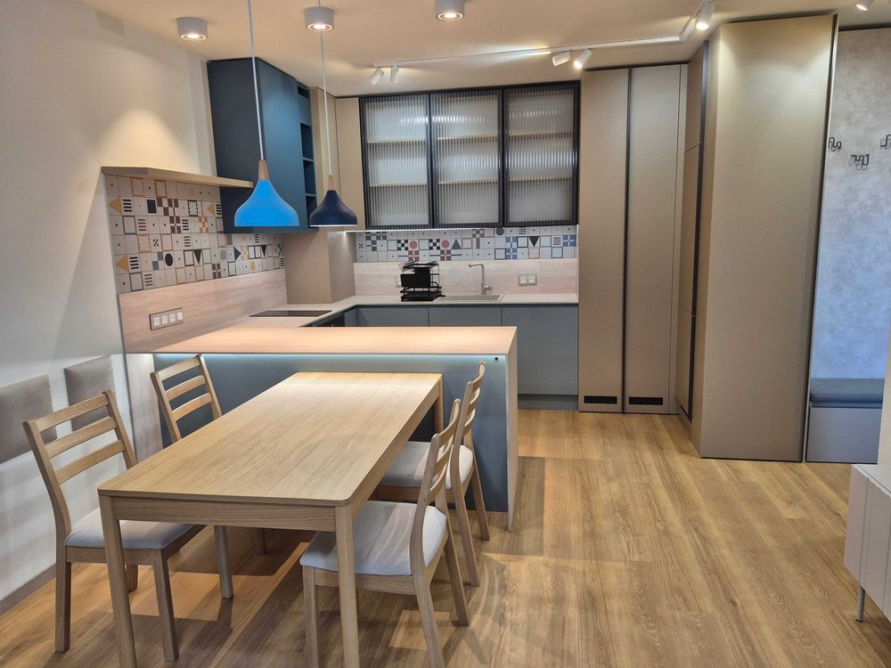 dvustaen-apartament-73-sqm-pod-naem-manastirski-livadi-sgrada-diada-2 Отворена кухня със сини пендели, трапезна маса и декоративна облицовка
