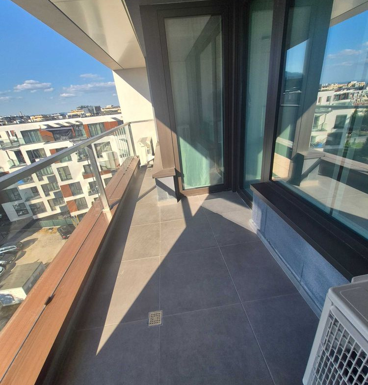dvustaen-apartament-73-sqm-pod-naem-manastirski-livadi-sgrada-diada-5 Тясна тераса с тъмни подови плочки, стъклена парапет, изглед към околни жилищни сгради
