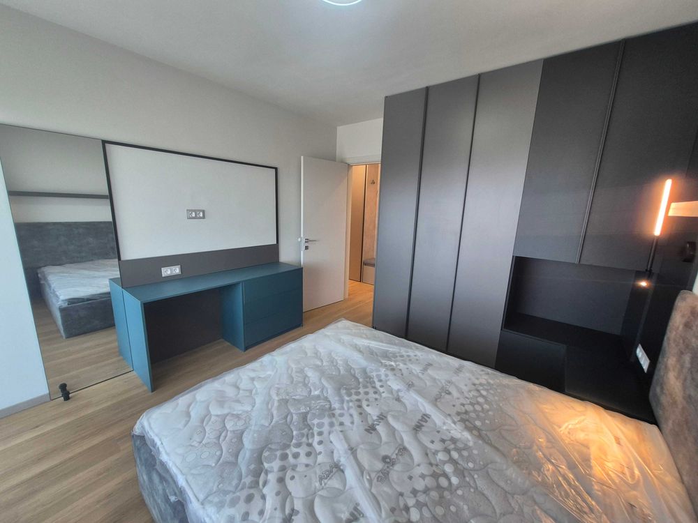 dvustaen-apartament-73-sqm-pod-naem-manastirski-livadi-sgrada-diada-7 Спалня от противоположен ъгъл с тъмен гардероб, синьо бюро, голямо огледало, отворена врата