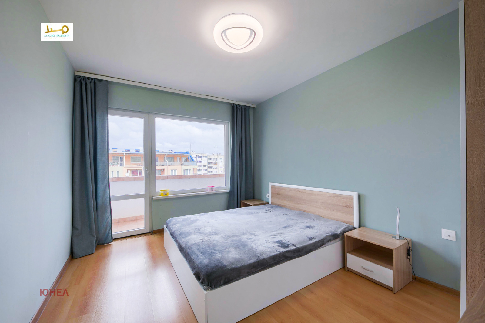 Bedroom with double bed, wooden headboard, nightstand and large window with curtains
