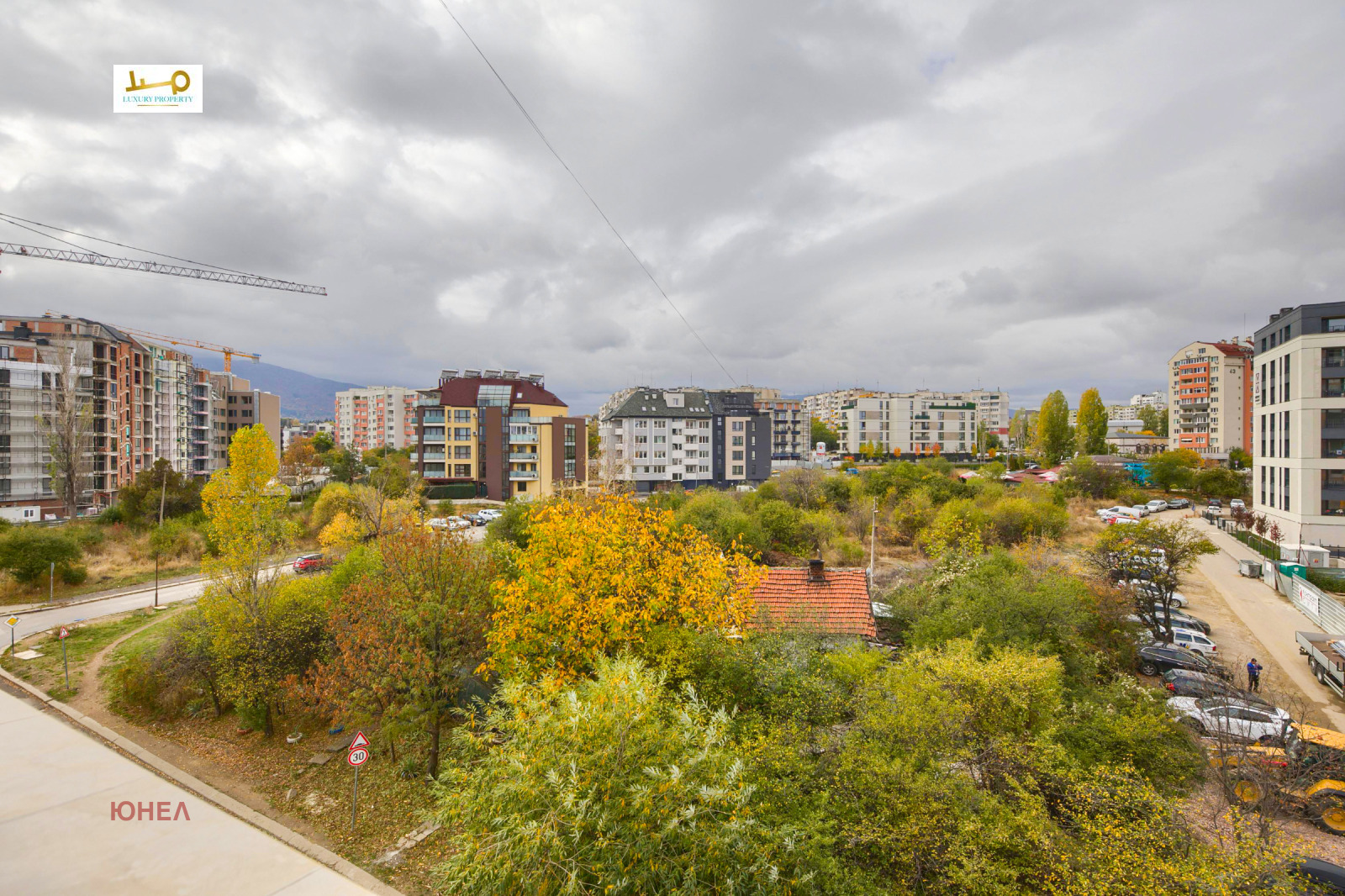 City view with autumn trees, residential and new apartment buildings, crane visible