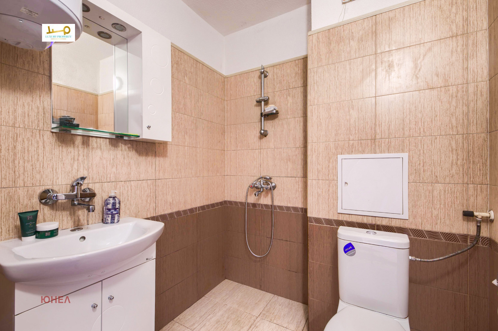 Bathroom with shower, toilet, vanity unit, mirror cabinet and beige wall tiles