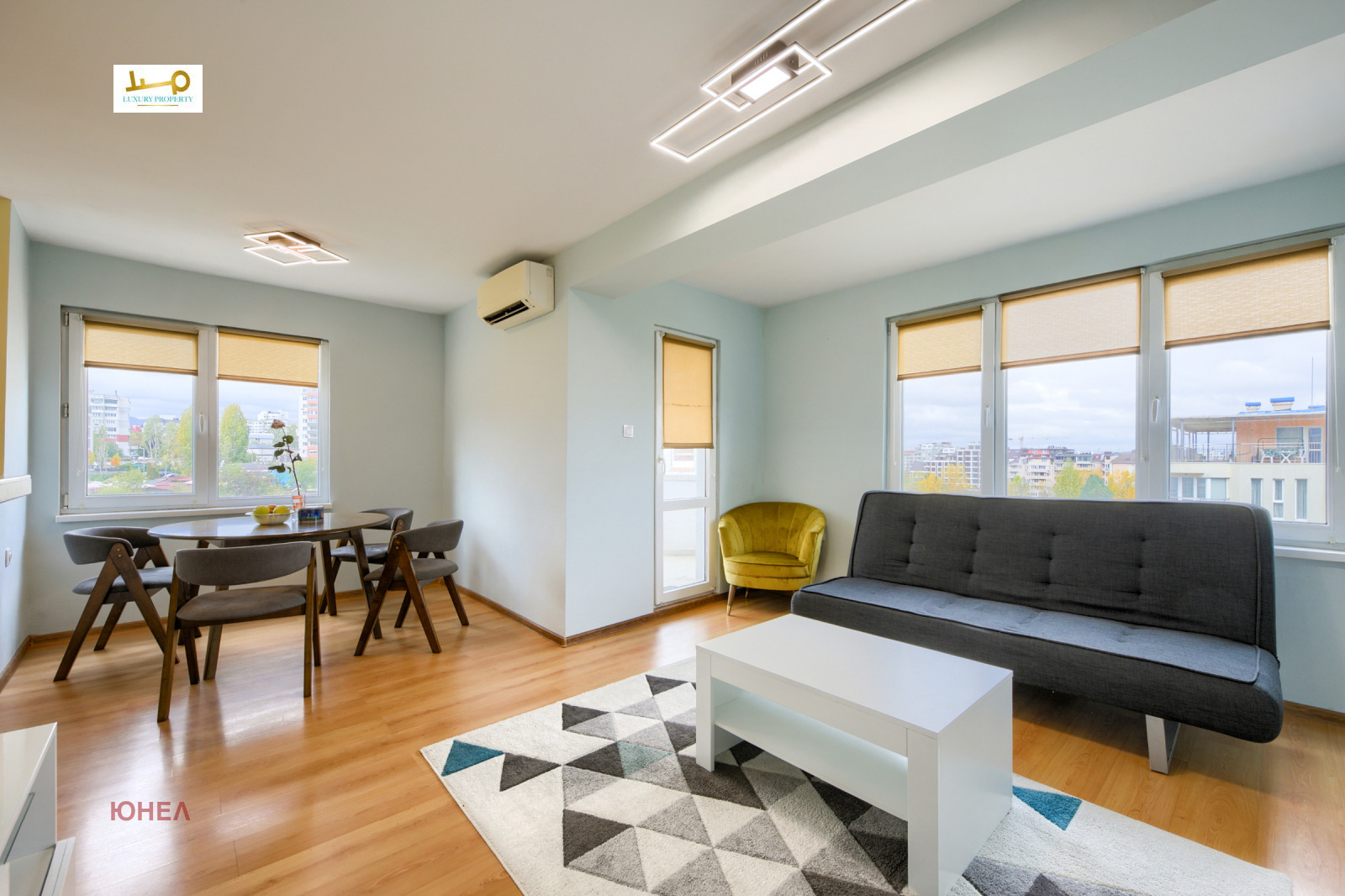 Living room with sofa, dining table, chairs, and windows