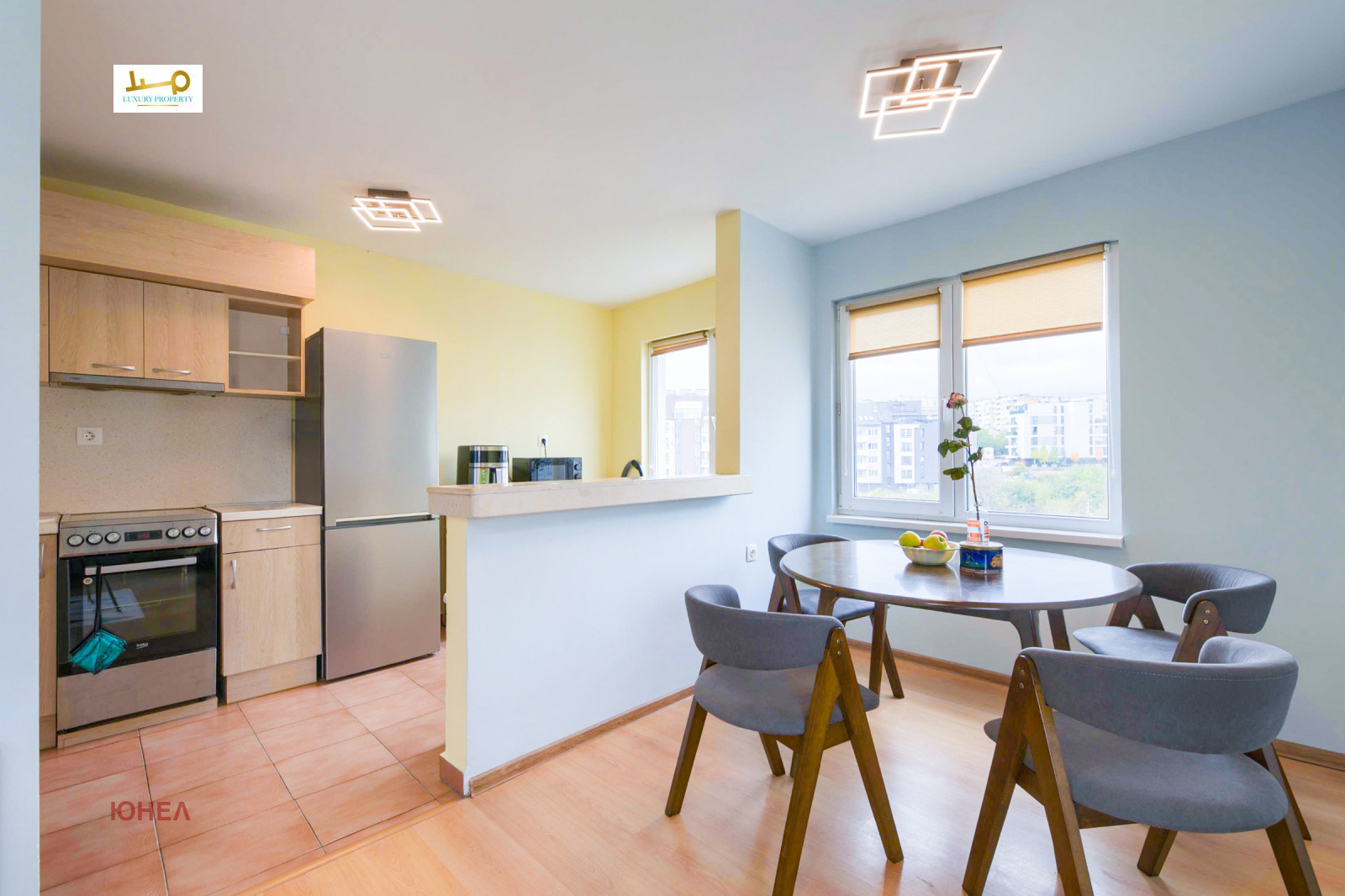 Kitchen with stove, fridge, wooden cabinets and round dining table with four chairs