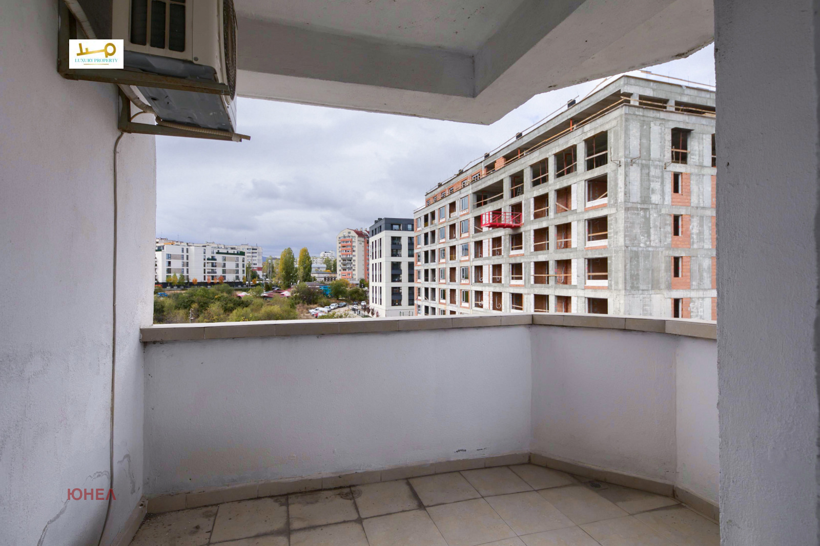 Open balcony with tiled floor, white walls and view of building under construction