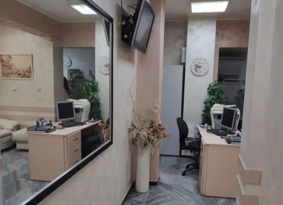 Corridor with large mirror, wall-mounted TV, and office desks