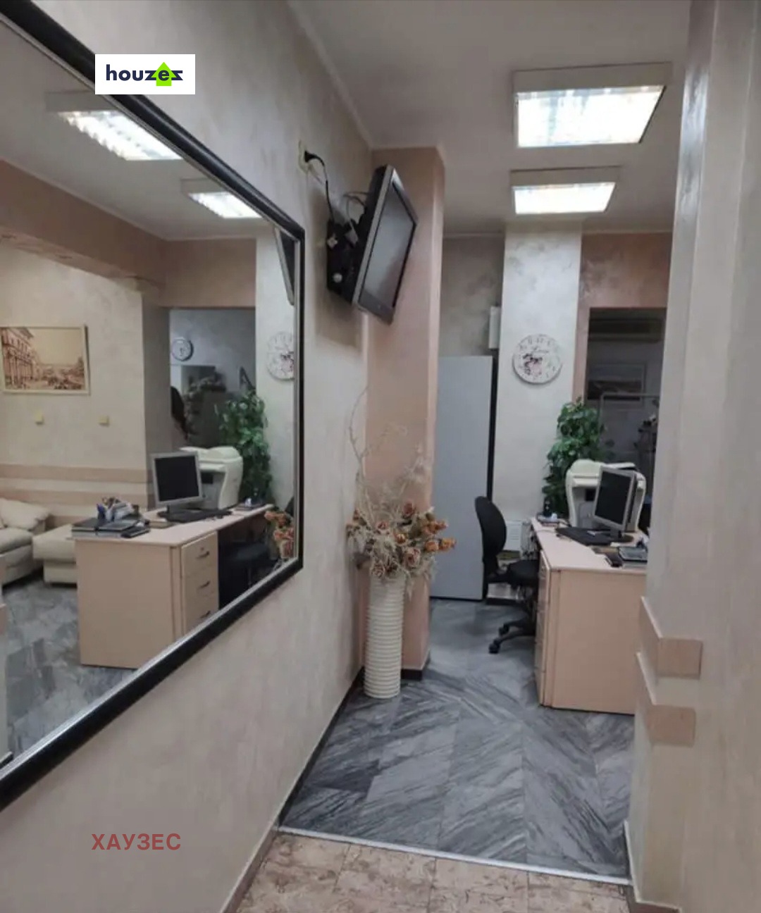 Corridor with large mirror, wall-mounted TV, and office desks