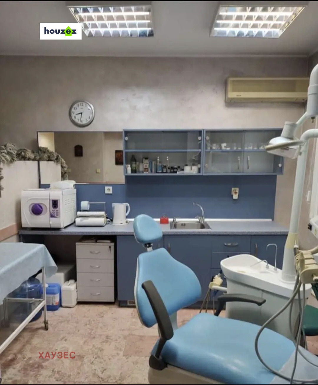 Dental office with blue cabinetry, autoclave, sink, and patient chair
