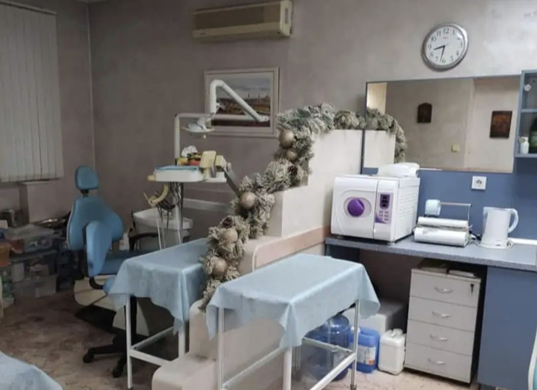 Dental treatment room with blue chair, medical tables, and autoclave