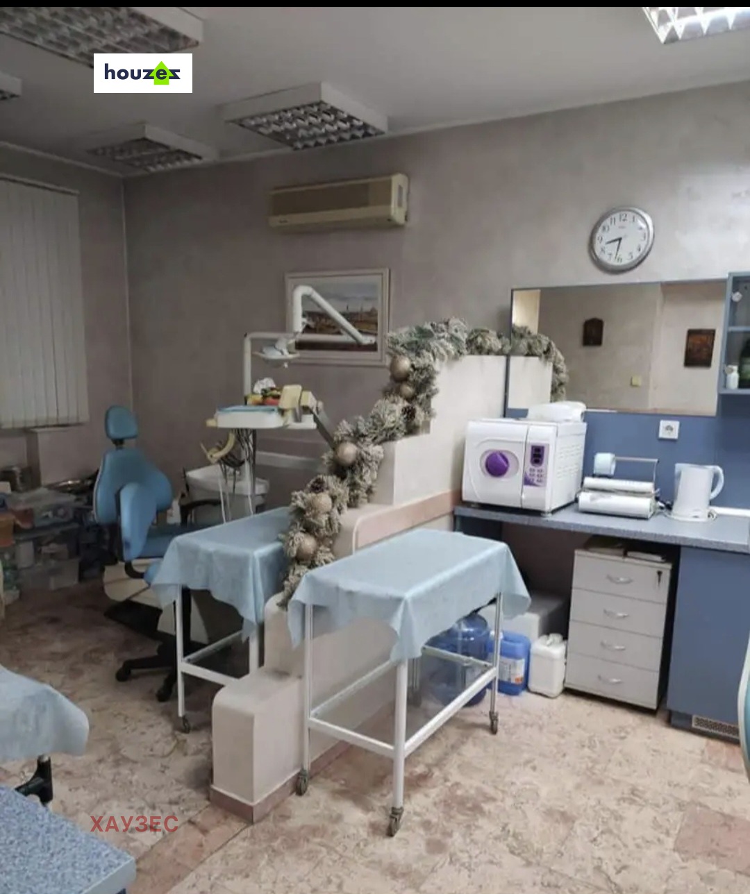 Dental treatment room with blue chair, medical tables, and autoclave