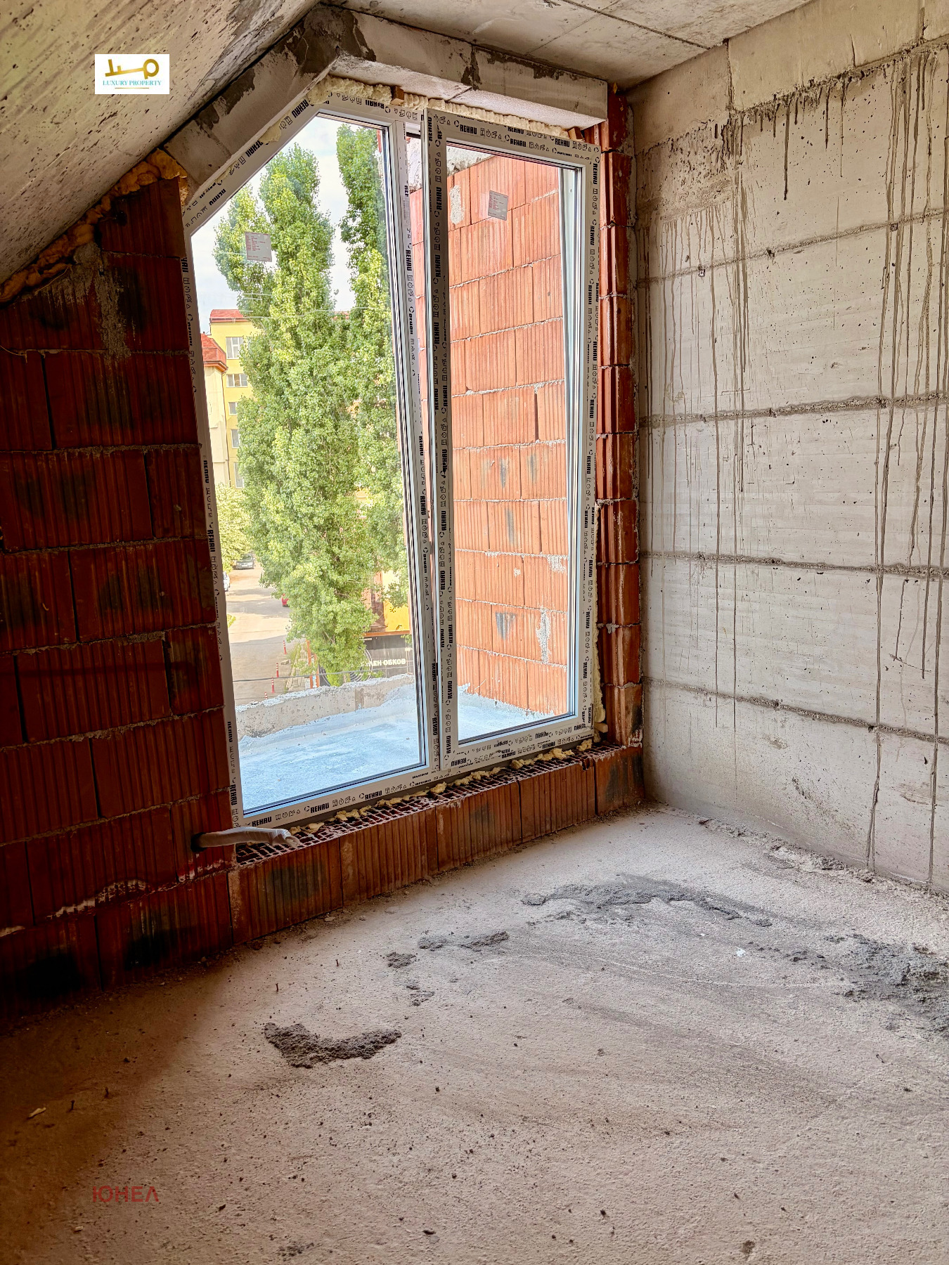 tristaen-apartament-108-sqm-za-prodazhba-ovcha-kupel-novo-stroitelstvo-6 Недовършена ъглова стая с наклонен таван, голям прозорец и изглед към дървета и улица