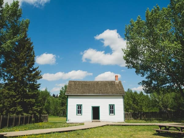 Малка къща за продажба на слънчев ден между две дървета